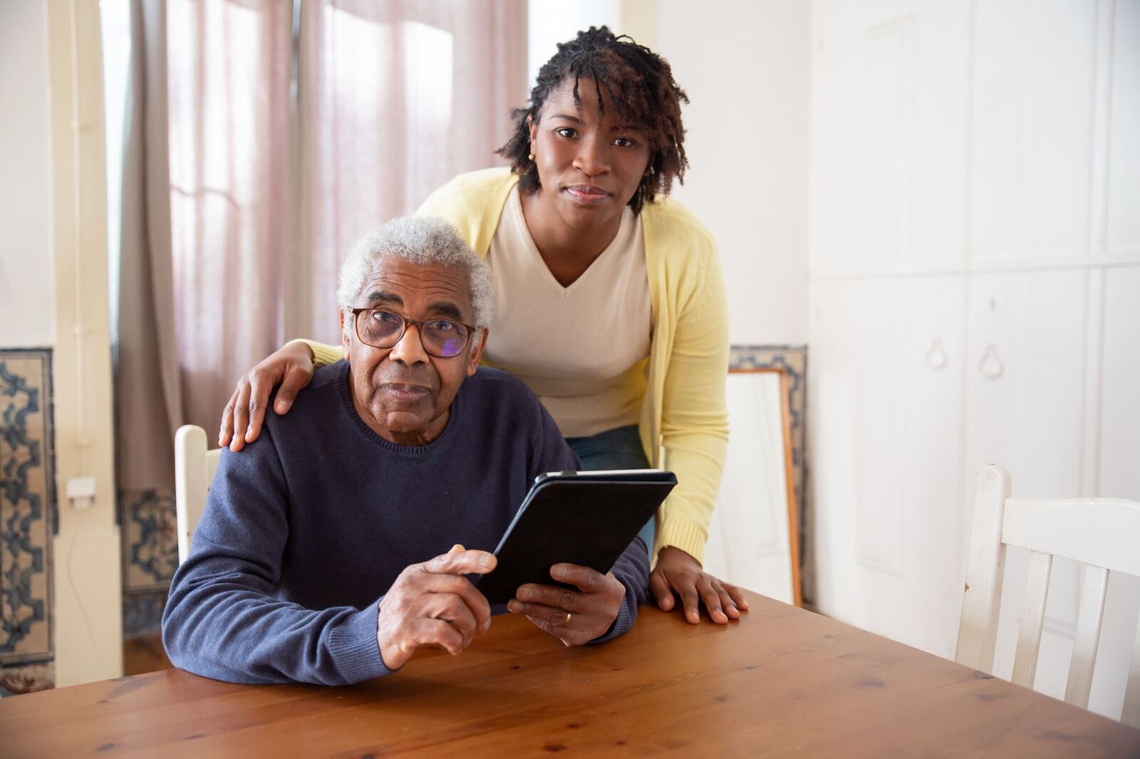 Caregiver helping an older adult use a tablet
